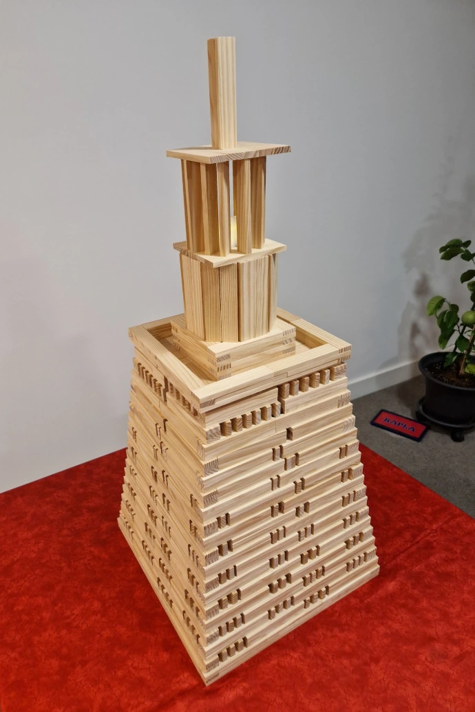 A tall, tiered Kapla structure representing the Alexandria Lighthouse, showcasing a stable, monumental design with a hollowed-out top for a light source.